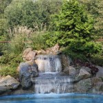 Backyard Design With Enchanting Backyard Design Including Pool With Clean Water And Artificial Waterfall On Stoney Background Also Grass Field And Trees At Beckside Garden  Backyard Garden Waterfalls As Beautiful Garden Landscaping 
