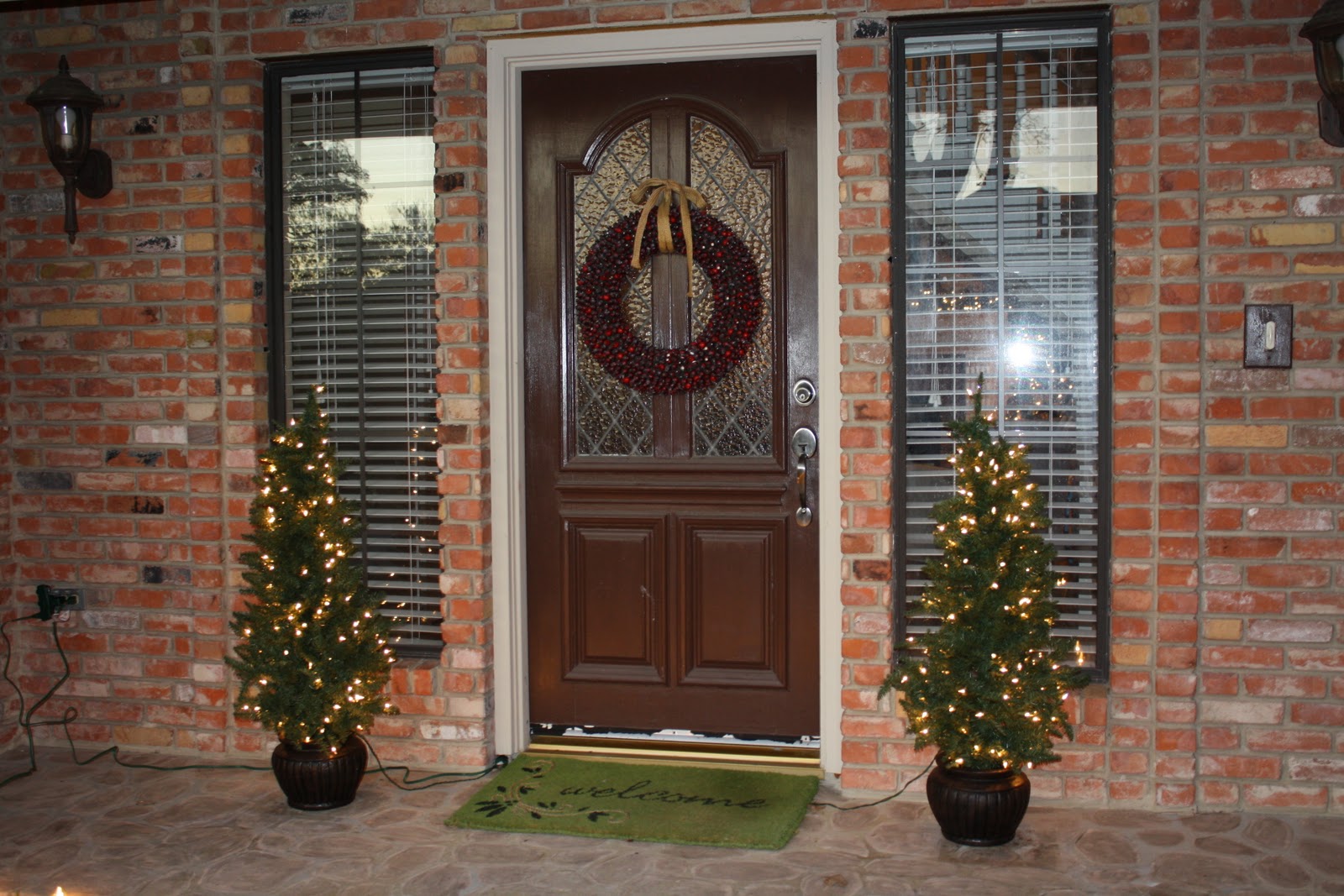 Entrance With And Appealing Entrance With Green Doormat And Dark Brown Front Door Ideas With Silver Door Lever Furnished With Christmas Decor And Completed With Wall Sconces Exterior Front Door Ideas: The “Face” Of The House