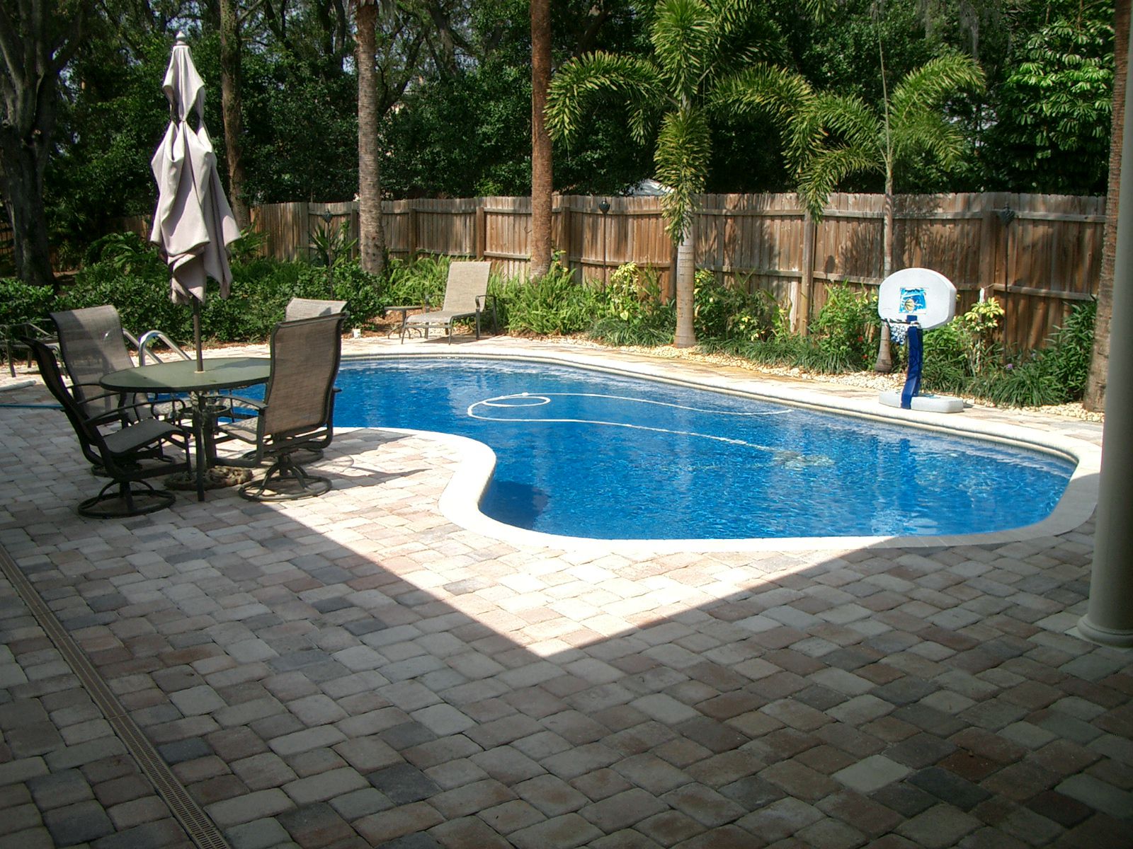 Pool Design Floor Backyard Pool Design With Paved Floor Round Table With Chairs Pool Side Chairs And Kiddies Basketball Ring Backyard Appealing Backyard Pool Designs For Contemporary Residences